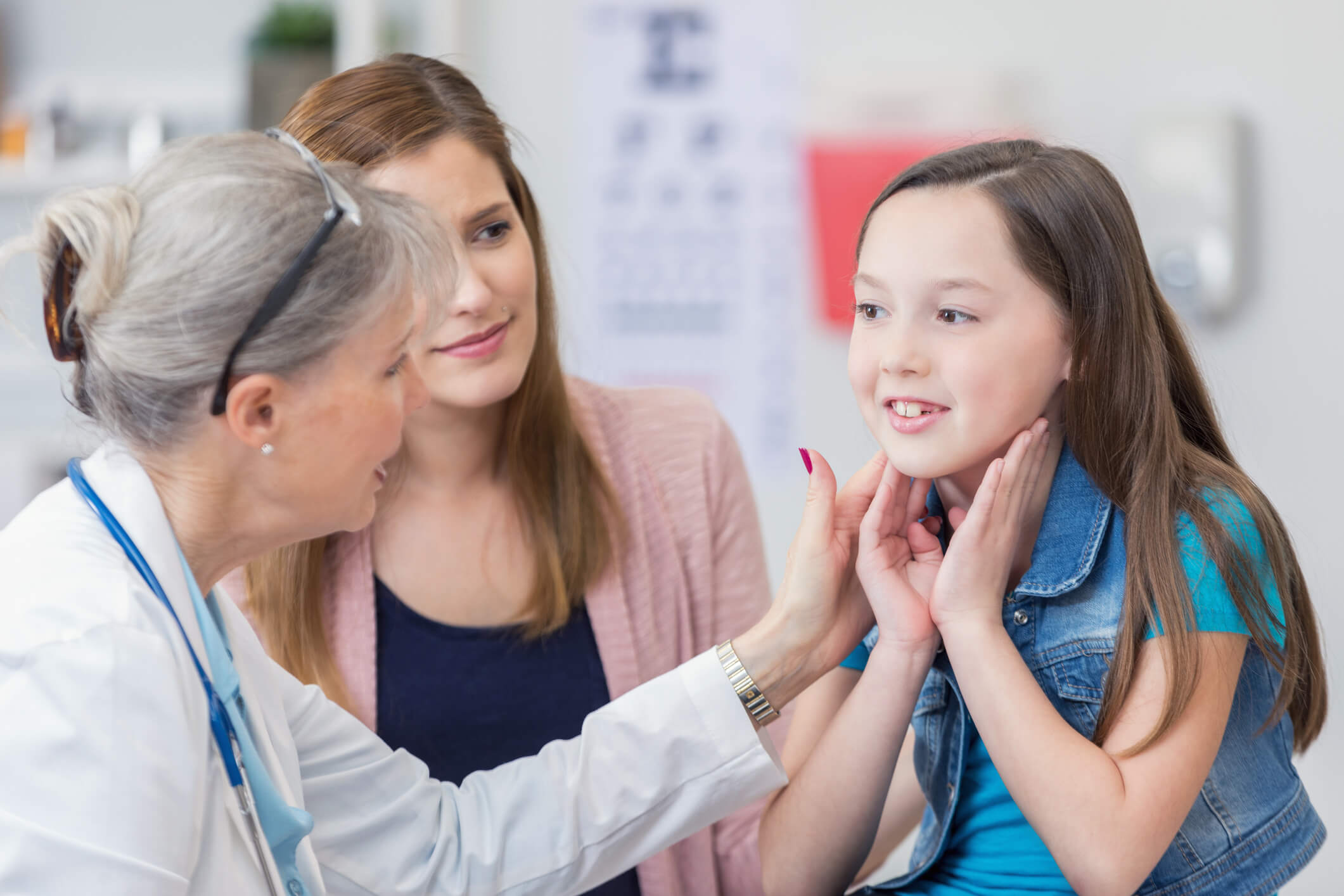 Confident senior female pediatrician examines young girl