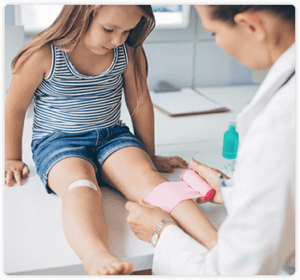 doctor at urgent care treating injured leg of a little girl