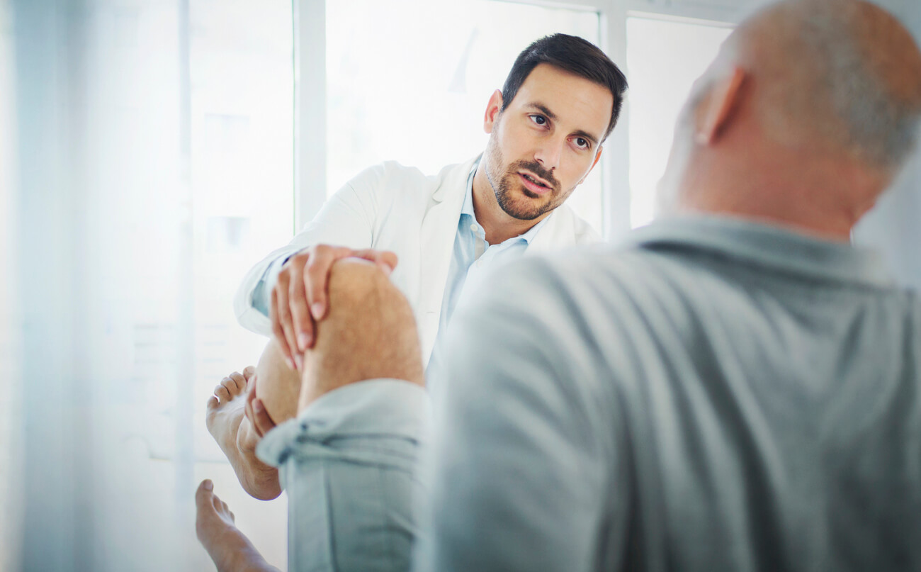 Senior man having his knee examined by a doctor