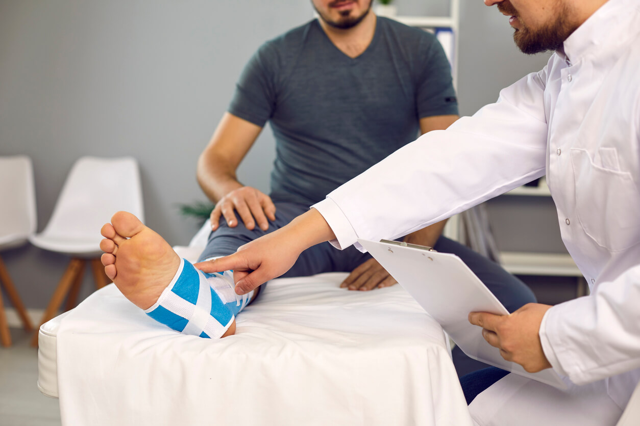 Doctor and patient with broken leg foot ankle in orthopedic care
