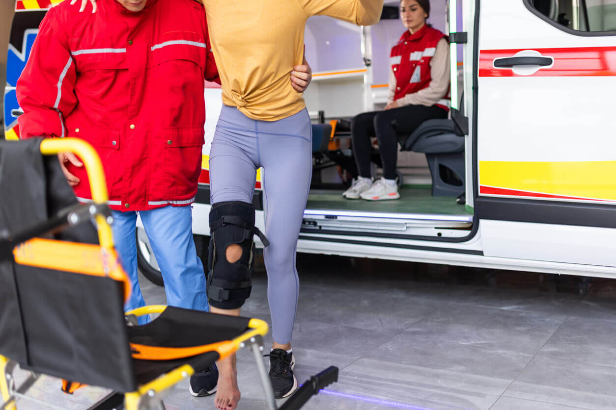 Paramedic helping young woman with injured leg at orthopedic urgent care center