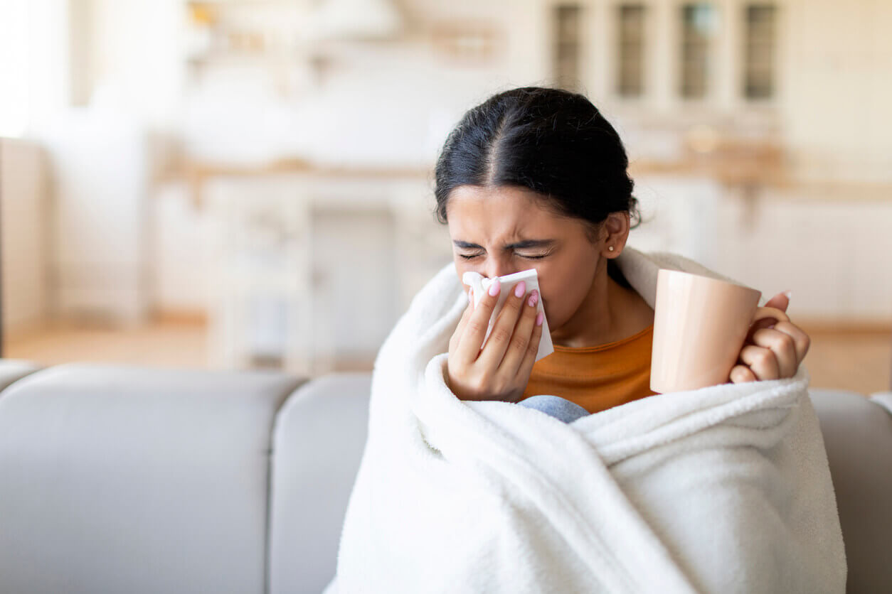 Sick indian woman covered in blanket blowing nose