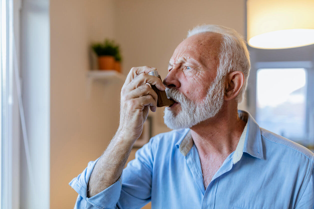 An elderly man is about to use his asthma inhaler after experiencing an allergic asthma attack.
