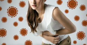Image of a woman clutching her stomach in pain due to a stomach virus or infectious disease like the stomach bug virus.