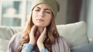 Image of a young woman suffering from a cold and experiencing throat pain due to strep throat.