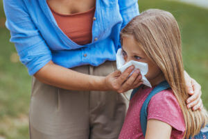 A caring mom is tending to her child's cold, which was caught from a common cold spread in school.